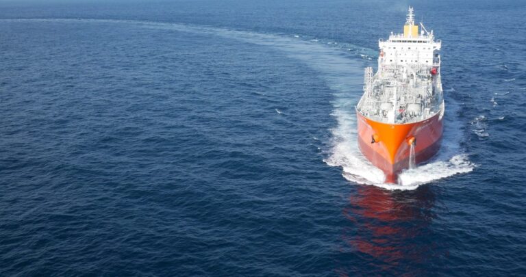 A wide shot of and front view of a ship sailing in a half circle into the picture frame
