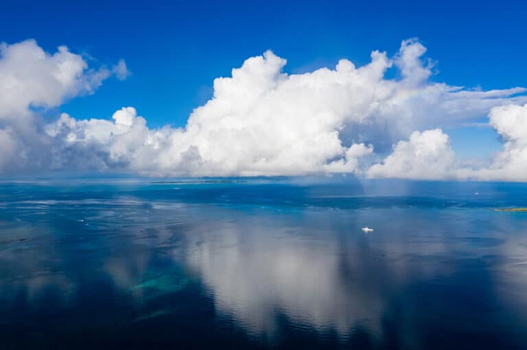 A wide shot of calm seas with big white fluffy clouds