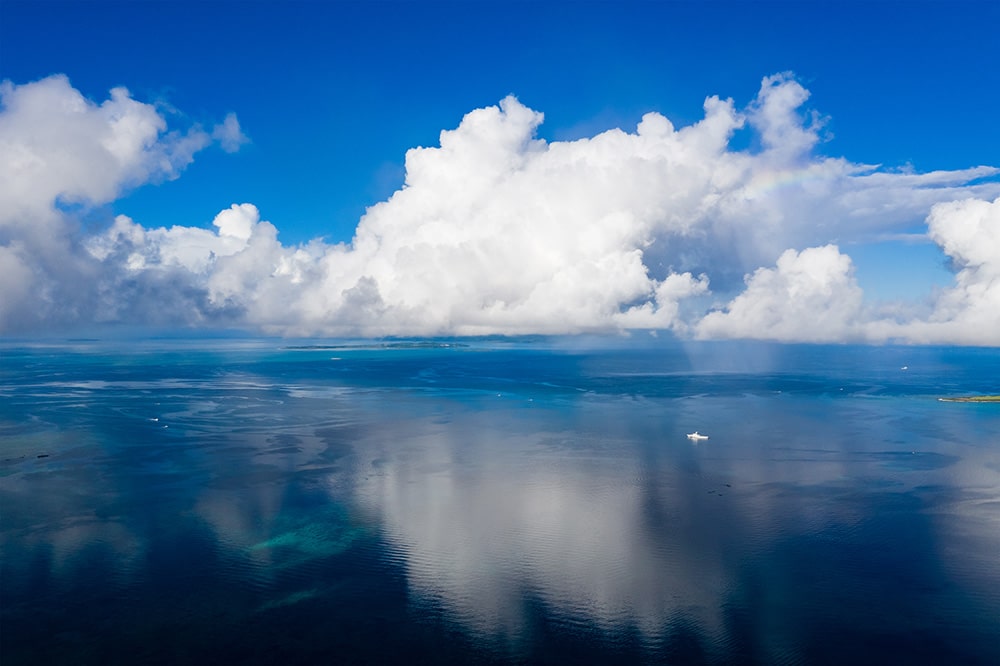 A wide shot of calm seas with big white fluffy clouds