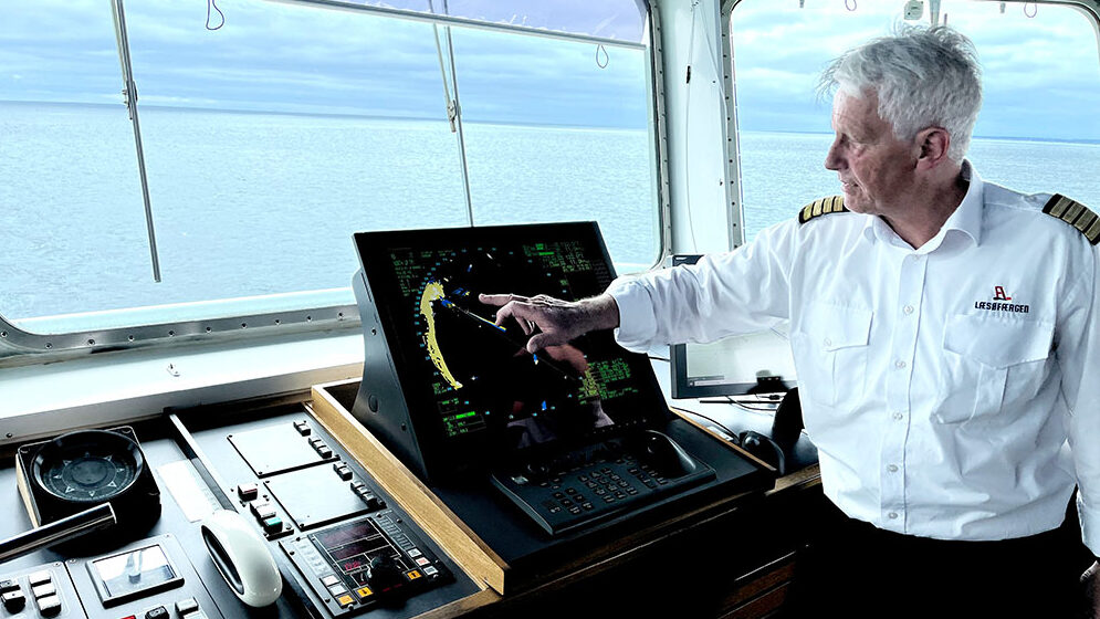 A picture of a maritime worker at Læsøfærgen sitting at a desk, surrounded by multiple screens displaying various data and controls