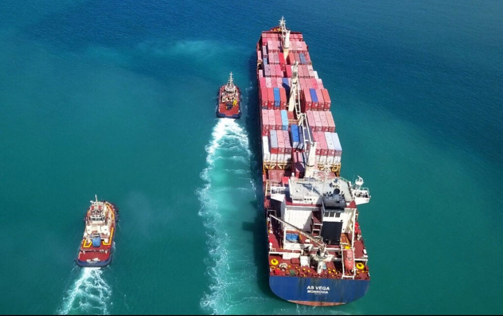 overview of a big tanker vessel with two support vessels sailing calm seas