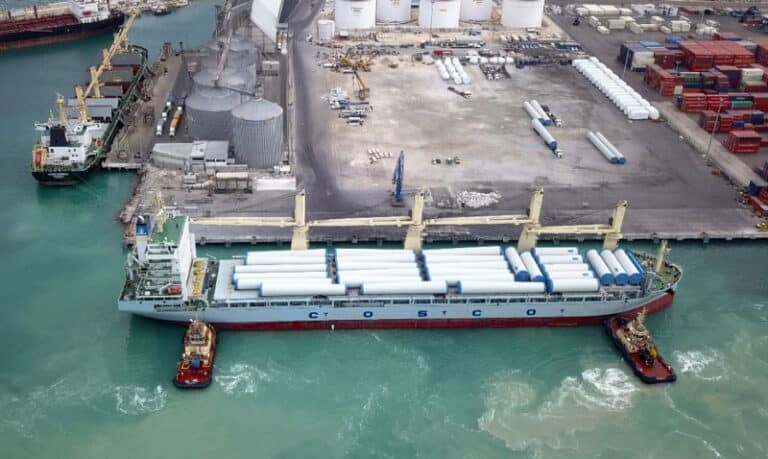 A photo of a maritime vessel being assisted in docking by two tugboats