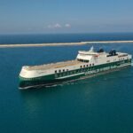 Una toma amplia desde el costado de un buque RoRo Híbrido Grimaldi deslizándose por un mar en calma.