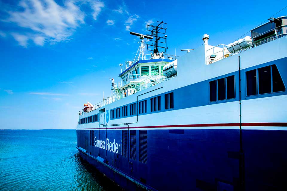A closeup along the side of a maritime vessel at sea, sailing blue calm sea under a blue sky