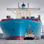 Vista frontal de un gran carguero que recibe apoyo de un remolcador